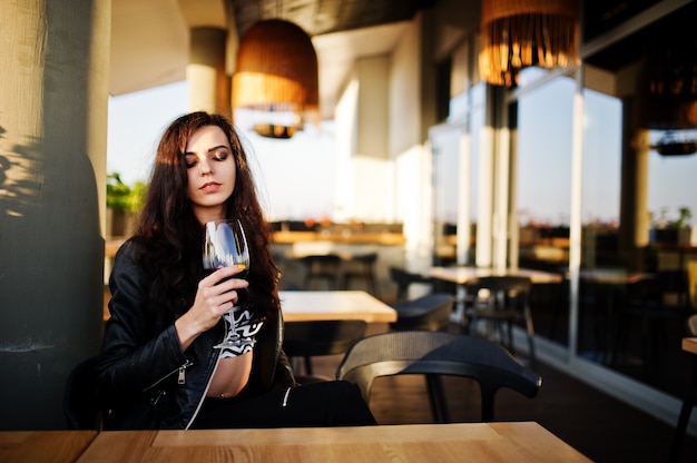 Young curly woman enjoying  her wine in a bar.