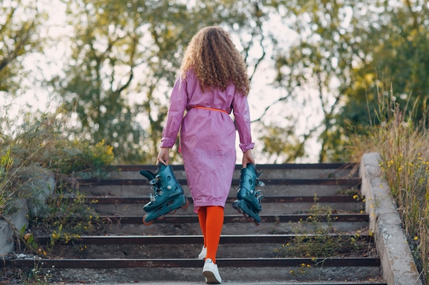 Young curly woman going roller skate at park.