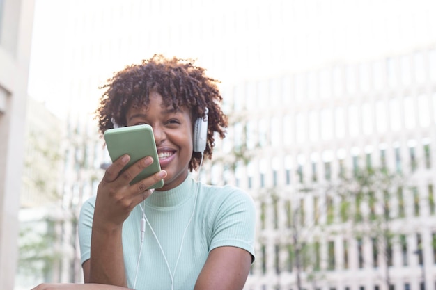 Young curly woman recording an audio message through her smartphone Latin teen with curly hair using her cell phone as a recorder to send a voice message to her mother