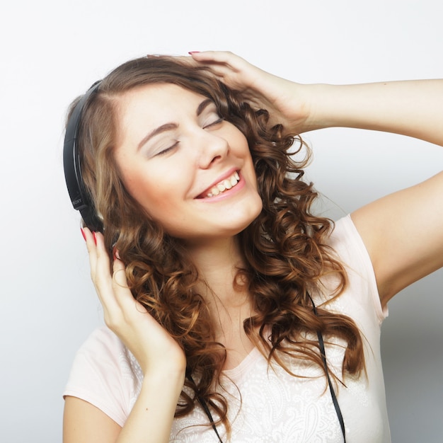 Young curly woman with headphones listening music.