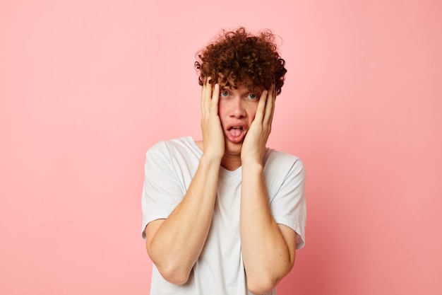 Young curlyhaired man posing youth style white tshirt pink background unaltered