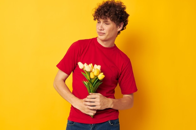 Young curlyhaired man in a red tshirt a bouquet of flowers holiday gift lifestyle unaltered