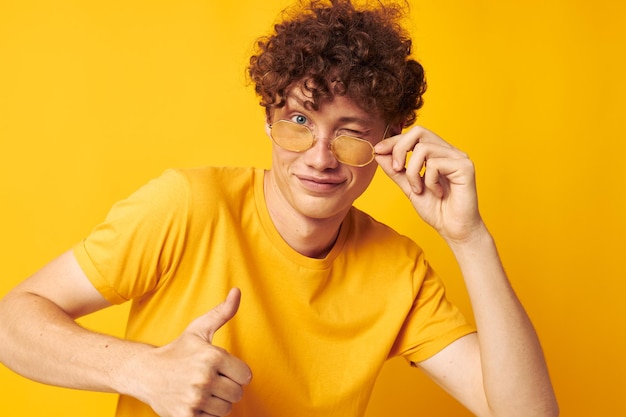 Young curlyhaired man wearing stylish glasses yellow tshirt posing monochrome shot