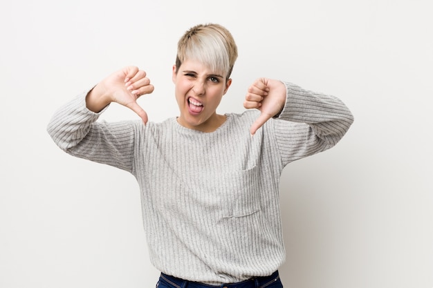 Young curvy caucasian woman isolated on white showing thumb down and expressing dislike.