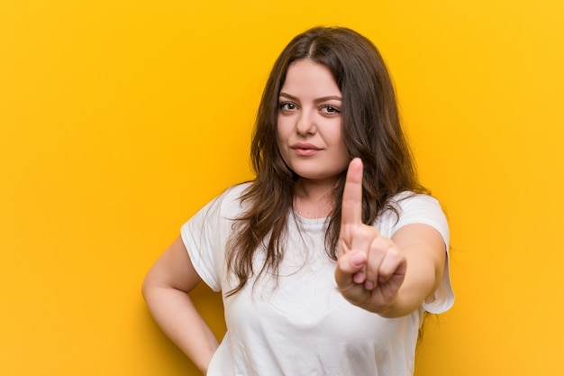 Young curvy plus size woman showing number one with finger.