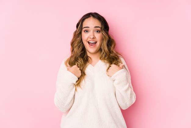 Young curvy woman posing surprised pointing with finger, smiling broadly