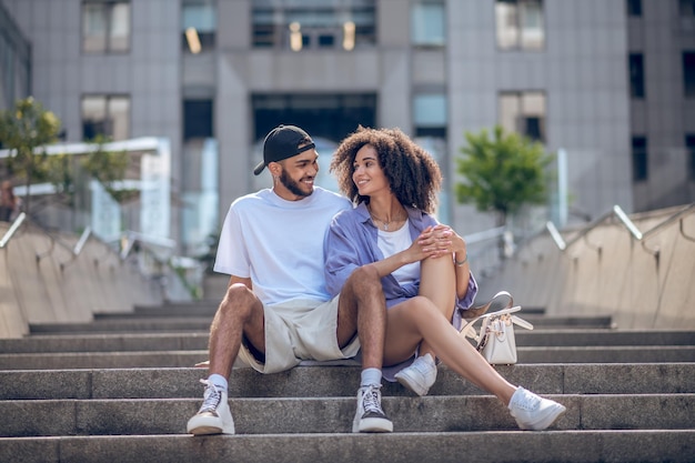 Young cute couple sitting on the steps and looking peaceful and happy