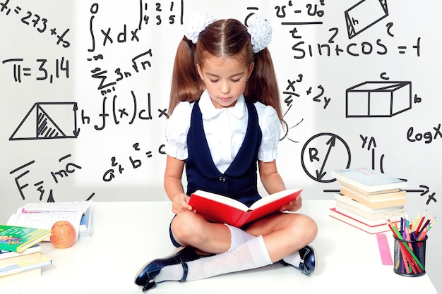 Young cute girl sitting at the table and reading a book