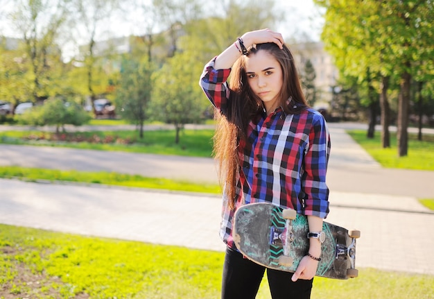 Young cute girl with skateboard on the surface of the Park