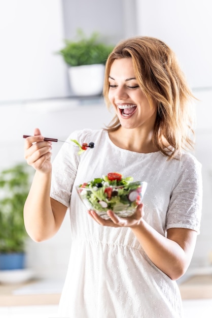 Young cute lady enjoys eating healthy salad