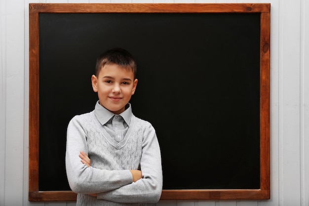 Young cute schoolboy posing at the blackboard