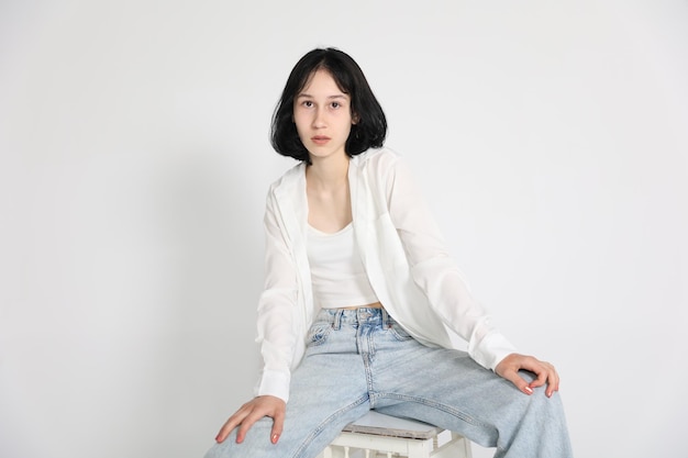 Young cute teen girl in jeans and shirt on a white background