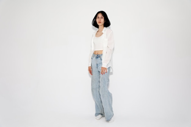 Young cute teen girl in jeans and shirt on a white background