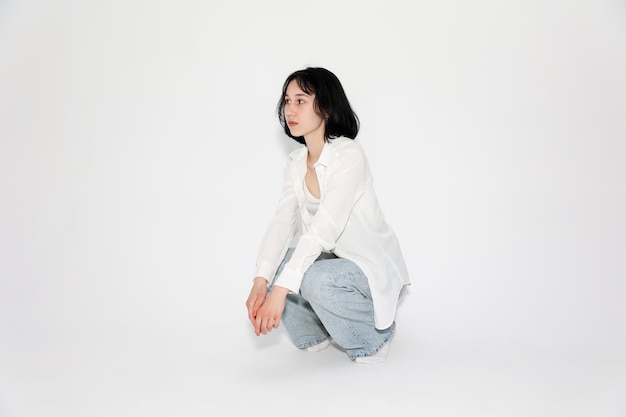 Young cute teen girl in jeans and shirt on a white background