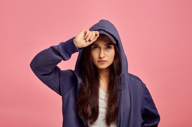 Young cute woman in hoodie, pink wall, emotion