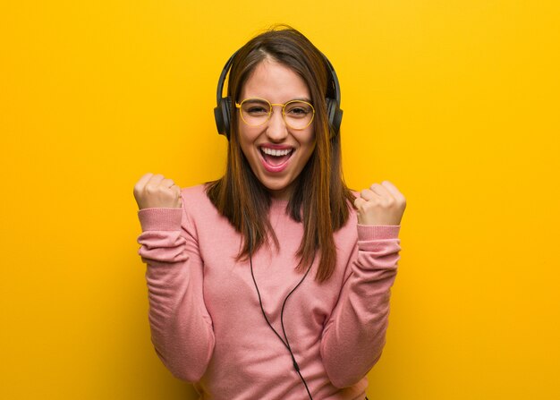 Young cute woman listening to music surprised and shocked