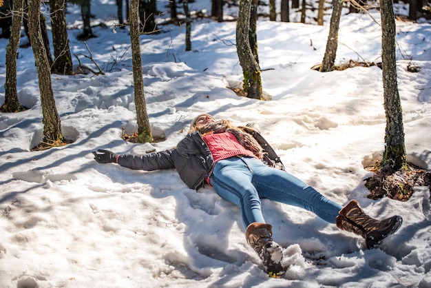 Young cute woman lying playing and enjoying snow in winter