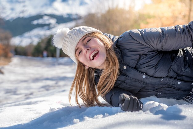 Young cute woman lying playing and enjoying snow in winter