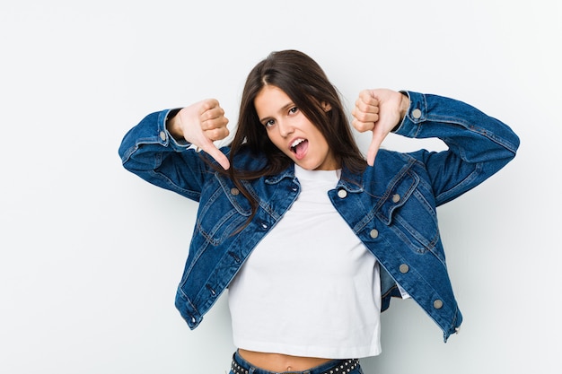 Young cute woman showing thumb down and expressing dislike.