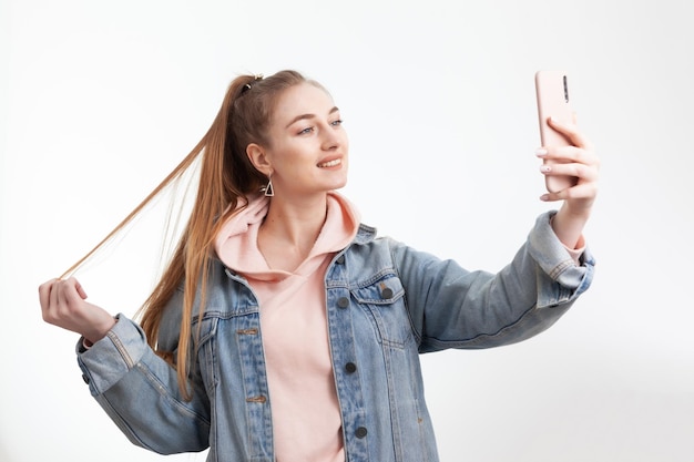 Young cute woman student makes selfie on smartphone isolated on white background