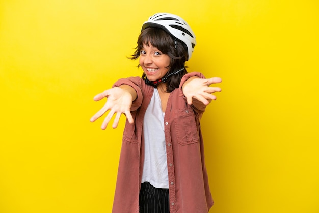 Young cyclist latin woman isolated on yellow background