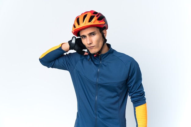 Young cyclist man isolated on wall having doubts