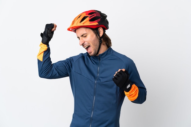 Young cyclist man isolated on white background celebrating a victory