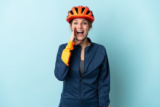 Young cyclist woman isolated on blue wall with surprise and shocked facial expression