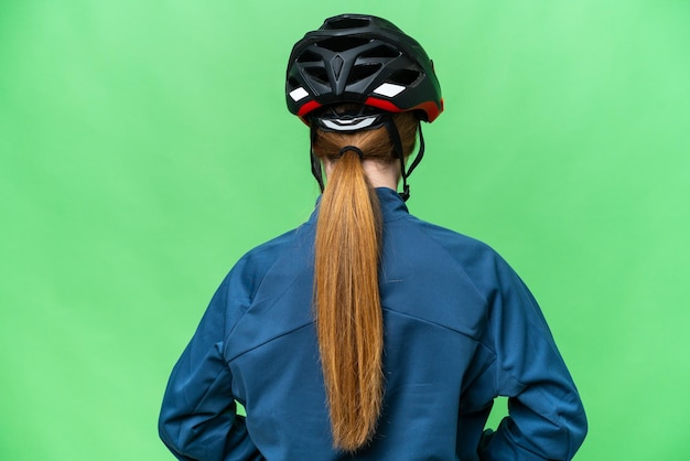 Young cyclist woman over isolated chroma key background in back position