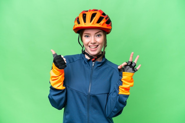 Young cyclist woman over isolated chroma key background showing ok sign and thumb up gesture