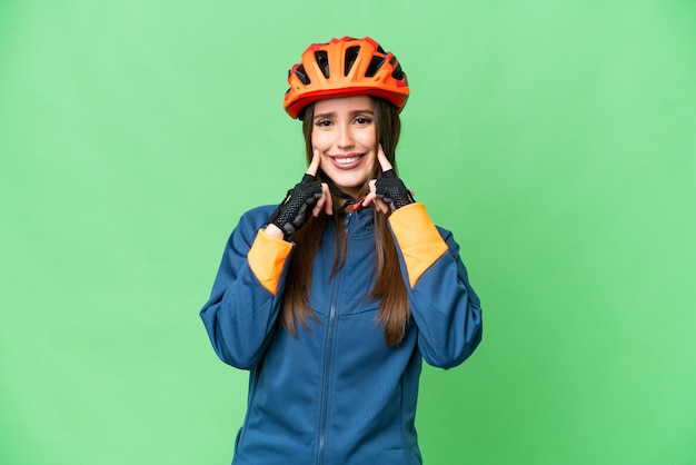 Young cyclist woman over isolated chroma key background smiling with a happy and pleasant expression