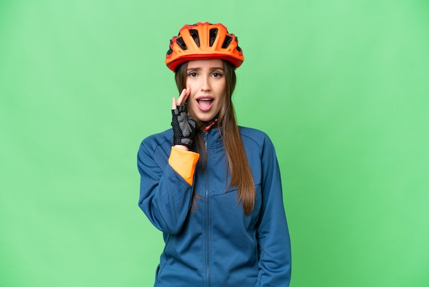 Young cyclist woman over isolated chroma key background surprised and shocked while looking right