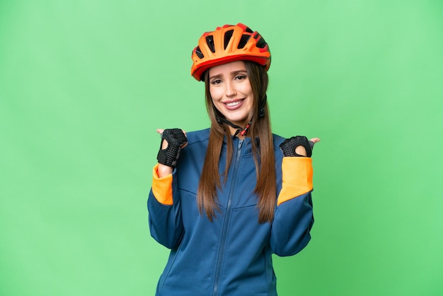 Young cyclist woman over isolated chroma key background with thumbs up gesture and smiling