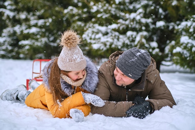 Young dad and his little cute daughter are having fun outdoor in snowy winter