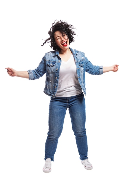 Young dancing plump girl. Beautiful curly brunette with red lips in jeans. Body positivity and freedom. Isolated on white background. Vertical.