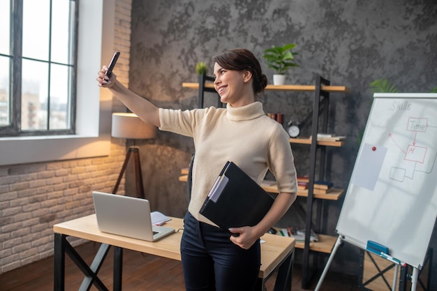 Young darkhaired woman having a video call and looking pleased