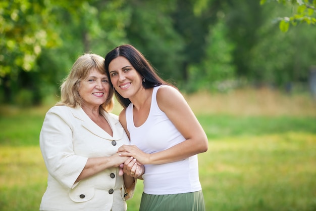 Young daughter with adult mother cuddling in a nature park