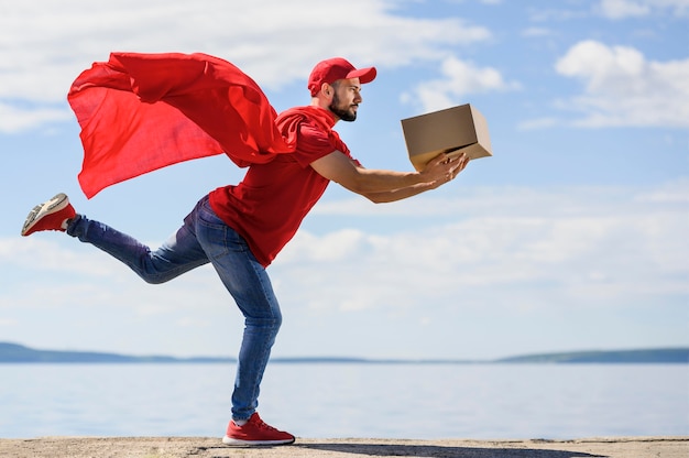 Young delivery man wearing superhero cape