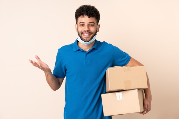 Young delivery Moroccan man isolated on beige background with shocked facial expression