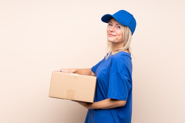 Young delivery woman over isolated wall laughing