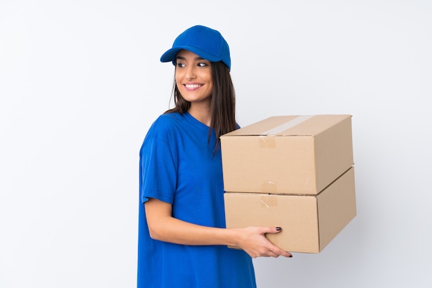 Young delivery woman over isolated white wall looking to the side