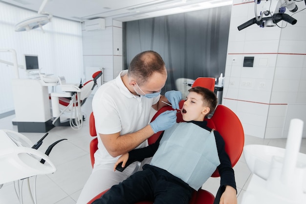 A young dentist examines and treats the teeth of an eightyearold boy in modern white dentistry closeup Dental prosthetics treatment and teeth whitening Modern dentistry Prevention