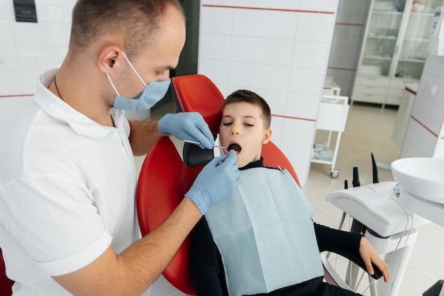 A young dentist examines and treats the teeth of an eightyearold boy in modern white dentistry closeup Dental prosthetics treatment and teeth whitening Modern dentistry Prevention