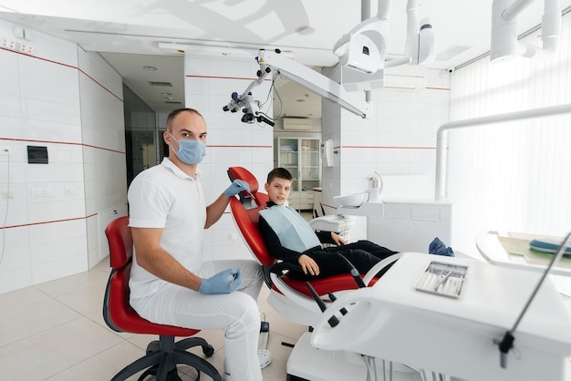 A young dentist examines and treats the teeth of an eightyearold boy in modern white dentistry closeup Dental prosthetics treatment and teeth whitening Modern dentistry Prevention