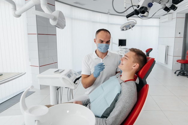 Photo a young dentist examines and treats the teeth of a young man in modern white dentistry closeup dental prosthetics treatment and teeth whitening modern dentistry prevention