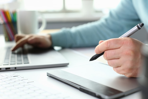 A young designer holds a pen from a tablet in his