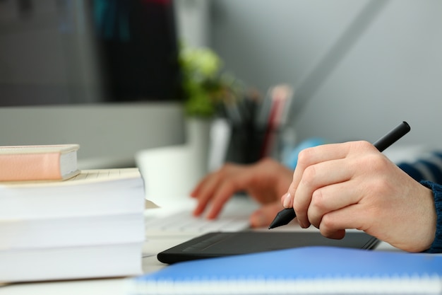 A young designer holds a pen from a tablet in his