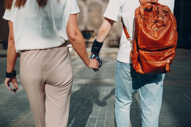 Young disabled man with artificial prosthetic hand walking and holding woman girlfriend hand