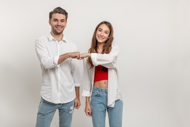 Young diverse couple give fist bump isolated over white wall background