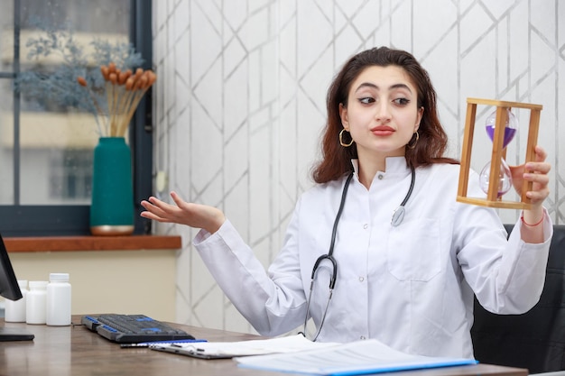 Young doctor holding sand clock and looking at it